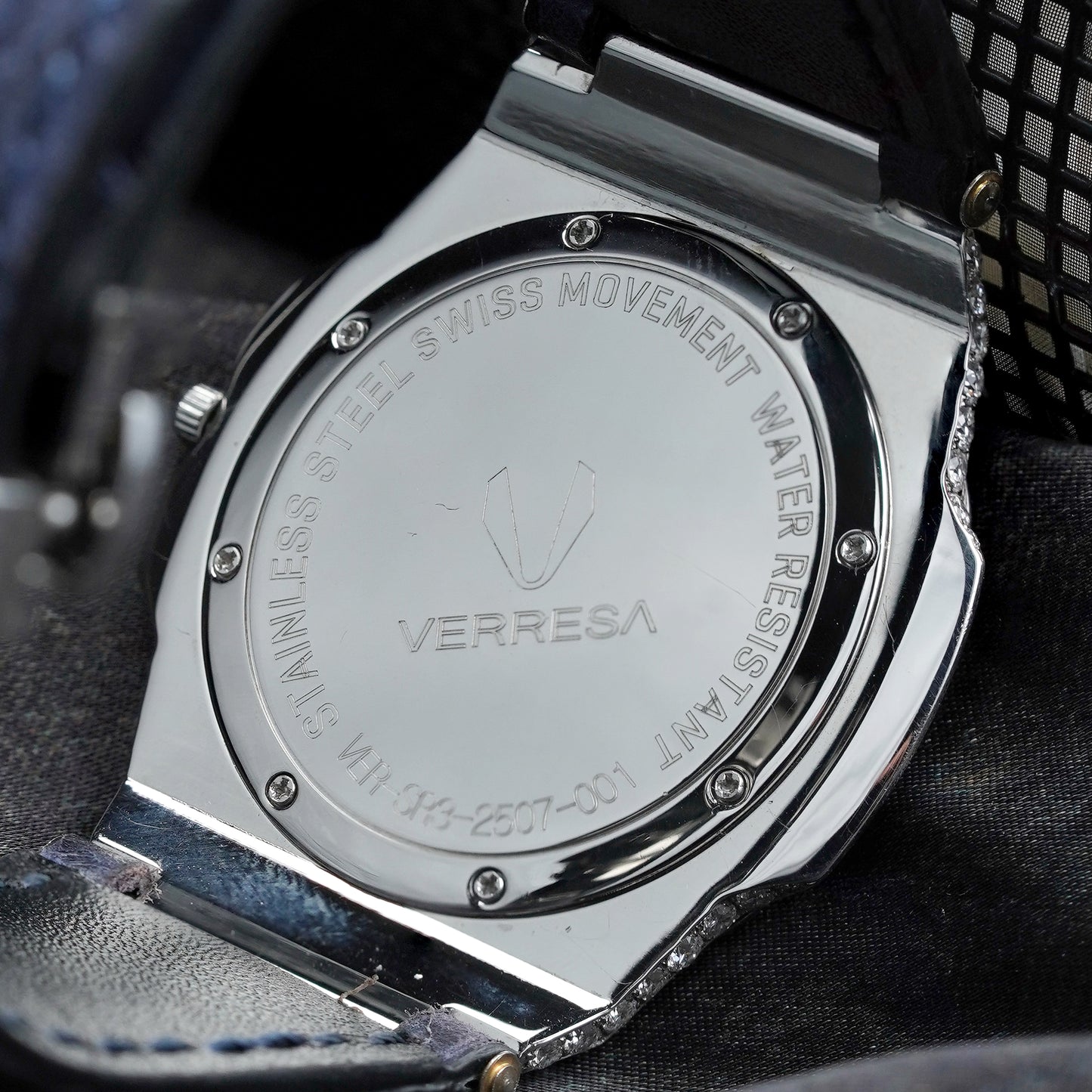 Close-up of a Verresa watch case with engraved text on a dark fabric background