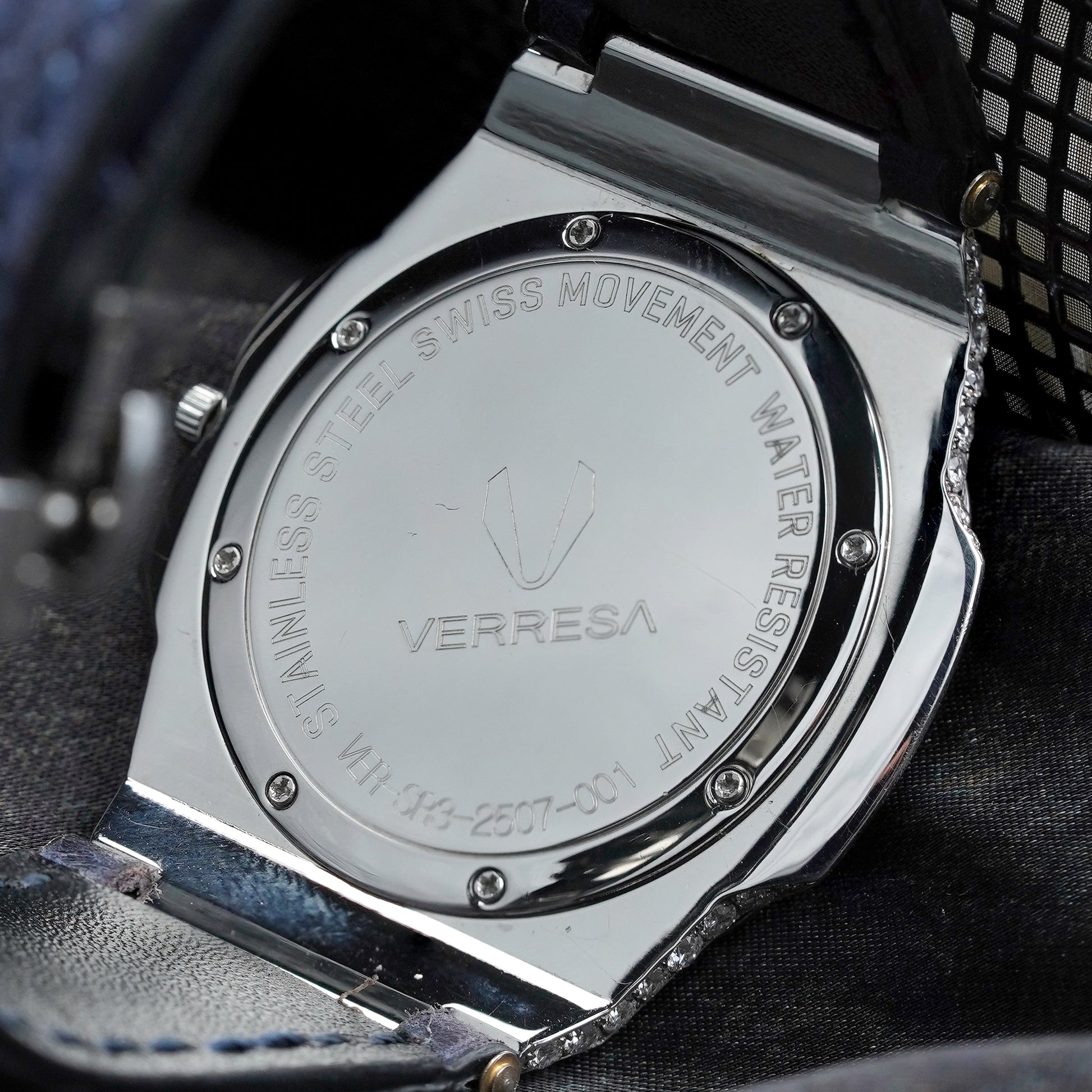 Close-up of a Verresa watch case with engraved text on a dark fabric background