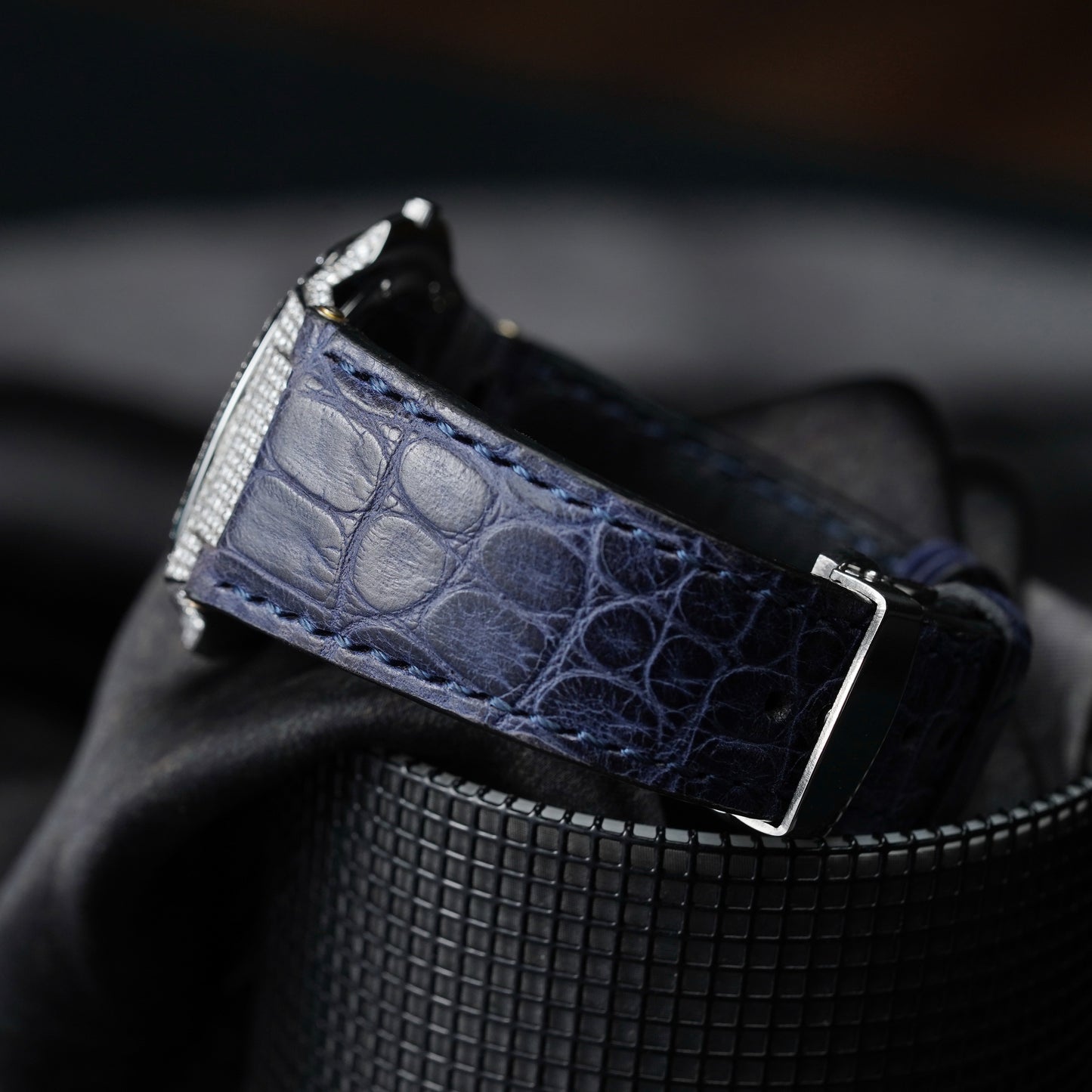Navy blue leather belt with silver buckle on a dark background
