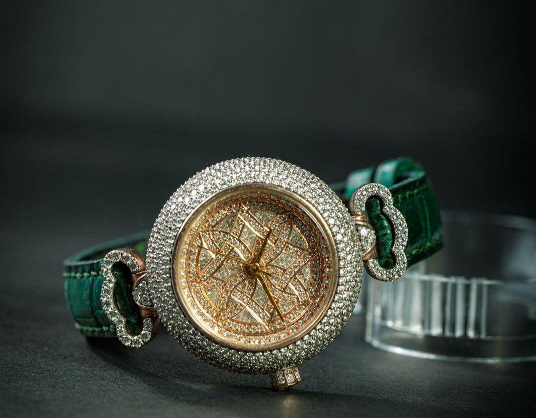Luxury watch with green strap and gold face on a dark background